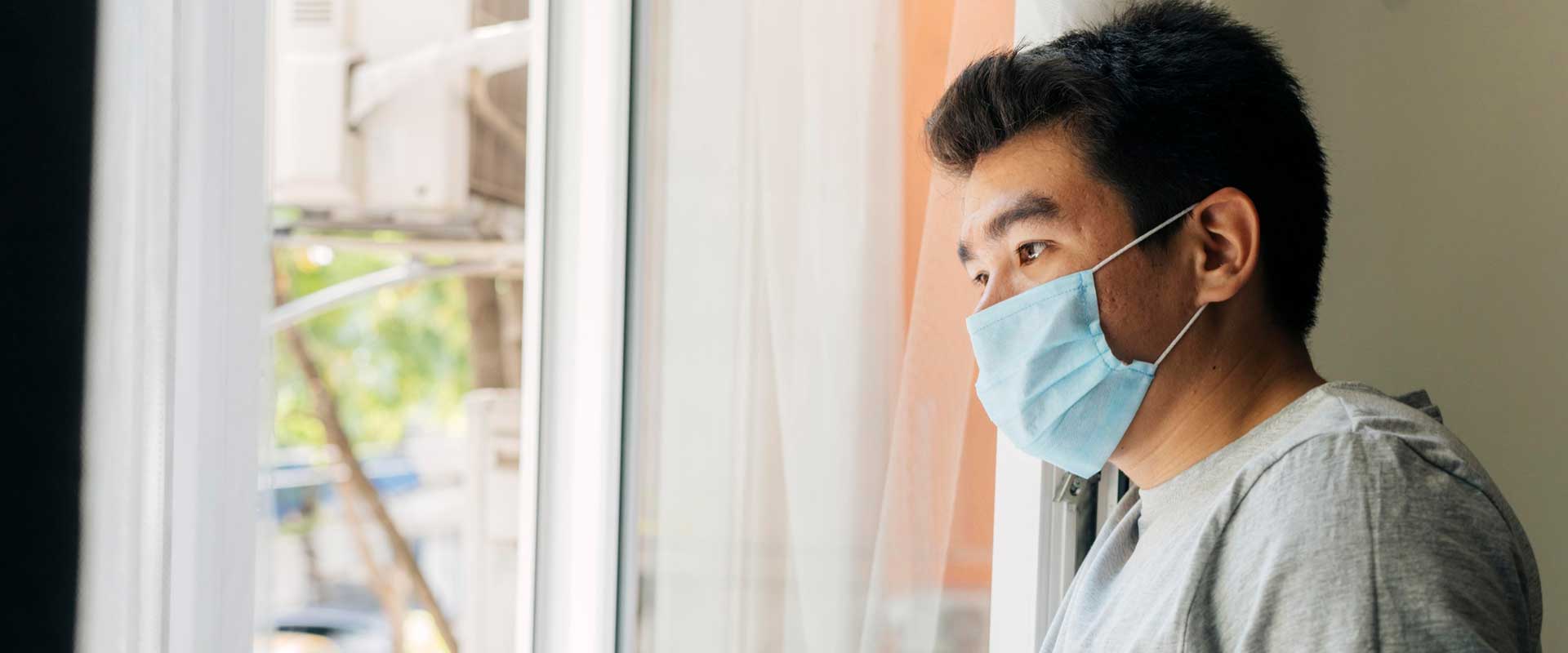 side-view-man-with-medical-mask-home-during-pandemic-looking-through-window